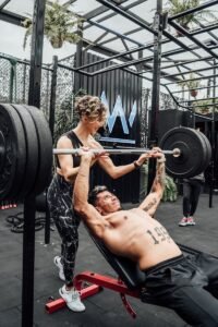 Muscular man and woman weightlifting at a modern Mexico City gym.