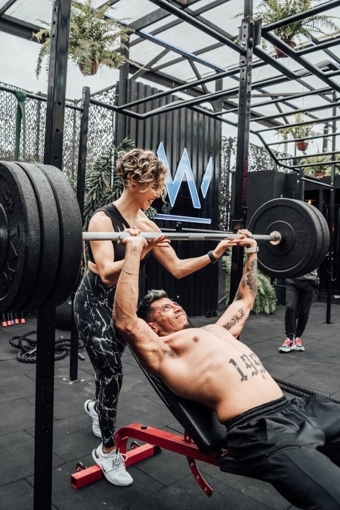 Muscular man and woman weightlifting at a modern Mexico City gym.