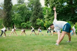 Kids stretching exercises in a park guided by a coach, promoting fitness and fun.